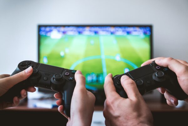 two video game controllers held in front of a TV