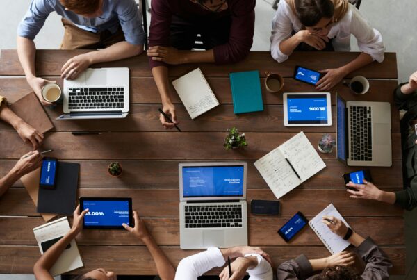 people working at a table full of laptops